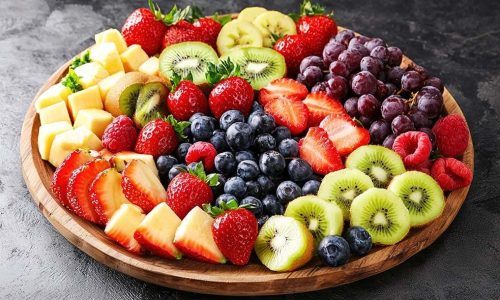 Fresh fruit and cheese platter on a wooden tray, perfect for healthy snacking or party appetizers